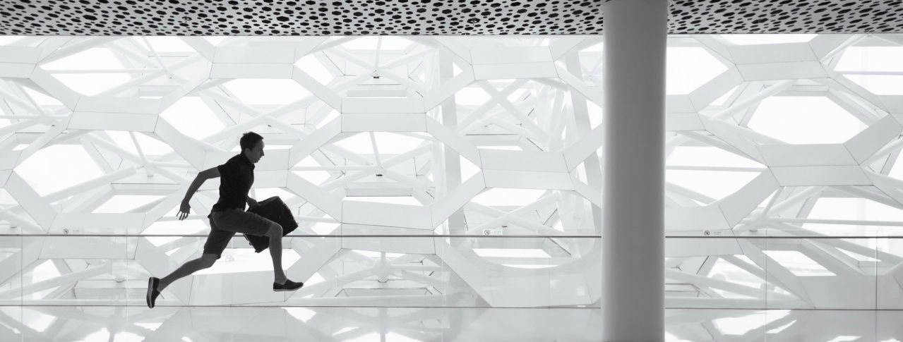 Mann mit Koffer rennt durch weiße Halle