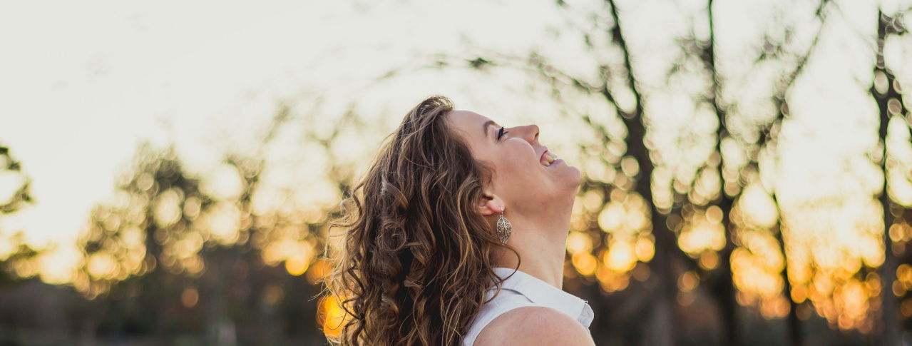 Frau schau hoch mit Bäumen im Hintergrund