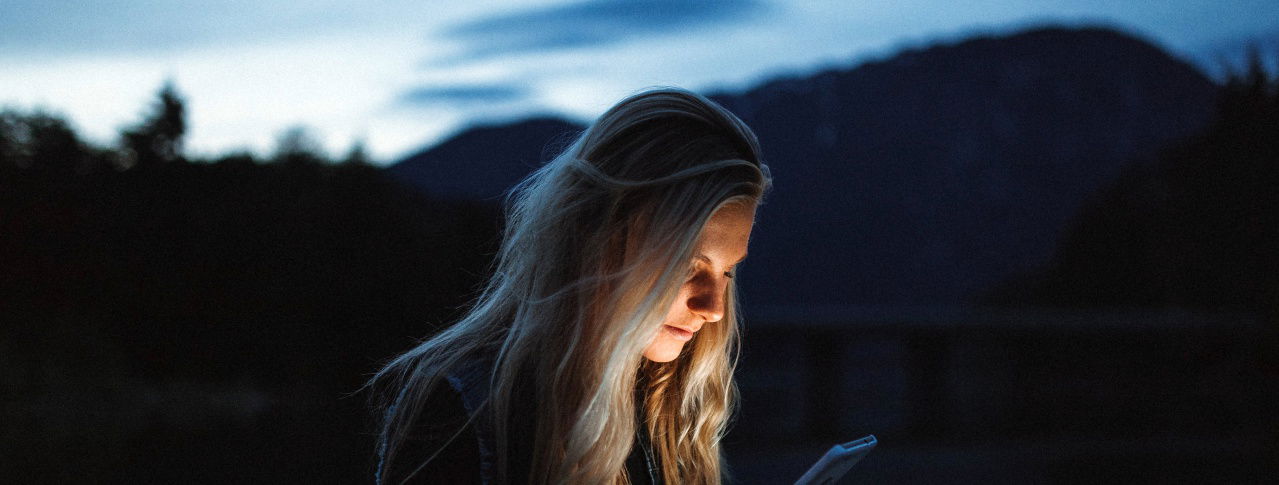 Frau mit blonden Haaren schaut auf ihr Handy 