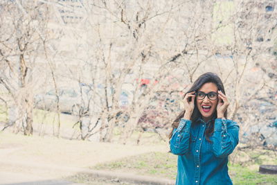 Frau mit Brille steht draußen und lacht 