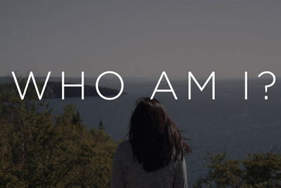 Frau schaut Meer an mit Schriftzug "Who am I?"