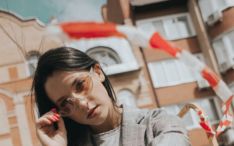 Frau hebt ihre Sonnenbrille und um sie herum fliegt ein Absperrband