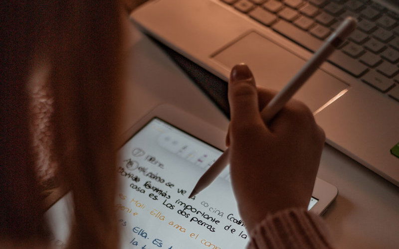 Mädchen arbeitet an ihrem Ipad und schreibt etwas auf 