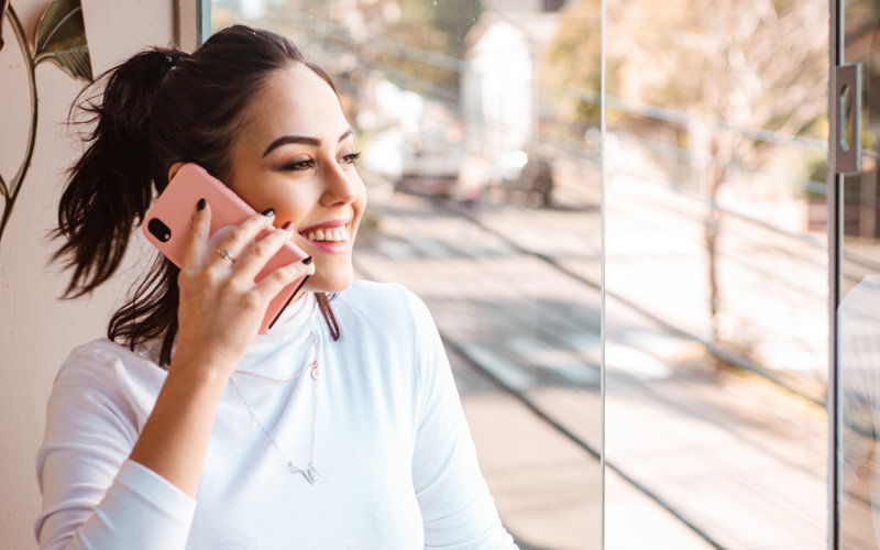 Frau telefoniert am Handy und schaut aus dem Fenster