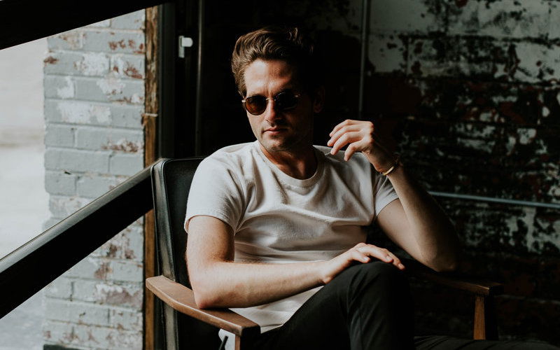 Mann mit Sonnenbrille sitzt aus Stuhl 