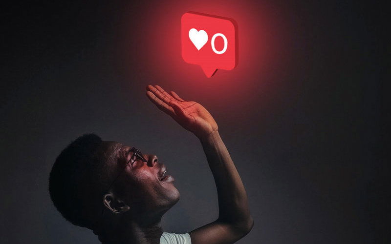 Mann mit Brille hebt seine Hand nach oben und hebt sie in Richtung einer roten Sprechblase mit einem Herz und einem Kreis