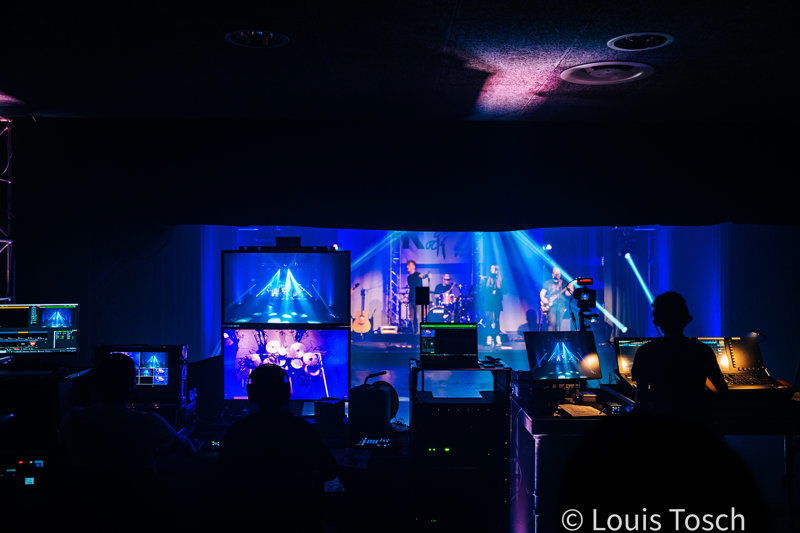 Band spielt auf einer Bühne und davor stehen viele Kameras und Technik 