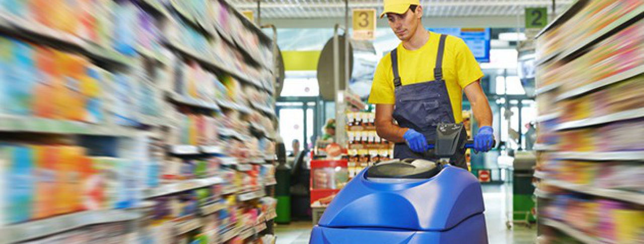 Mann im Einkaufsladen am Bodenwischen mit einer Maschine