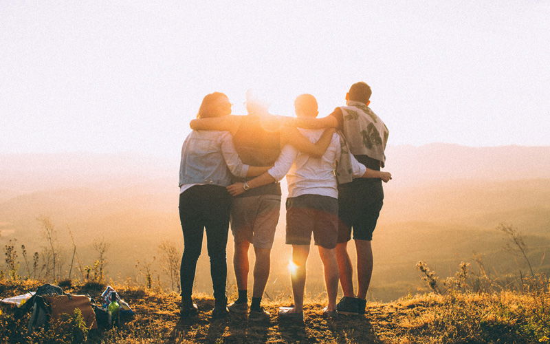 Gruppe Männer steht vor Sonne und hält sich fest
