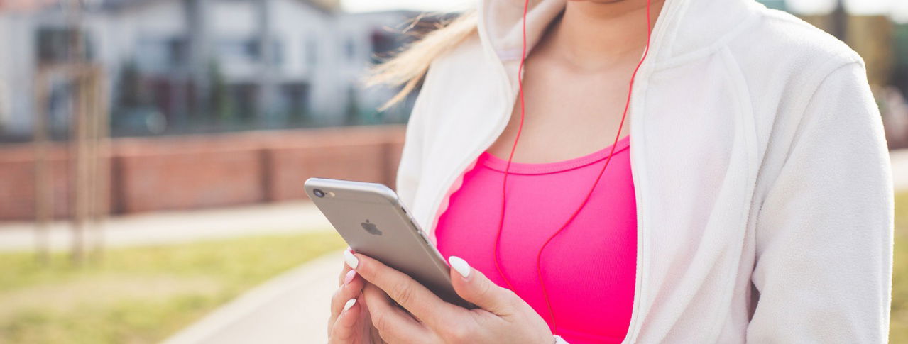 Frau mit pinkem Top und Handy in der Hand
