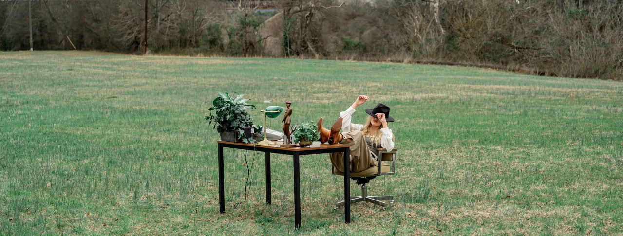 frau auf wiese mit tisch und stuhl