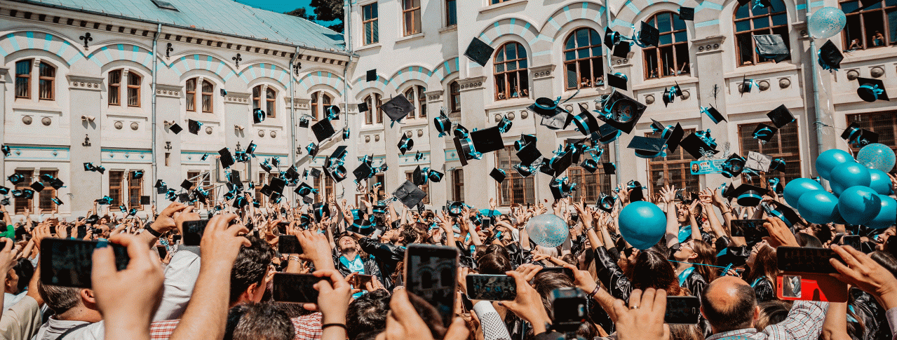 Studenten die ihr Studium geschafft haben und ihre Hüte in die Luft schmeißen, sowie viele Kameras