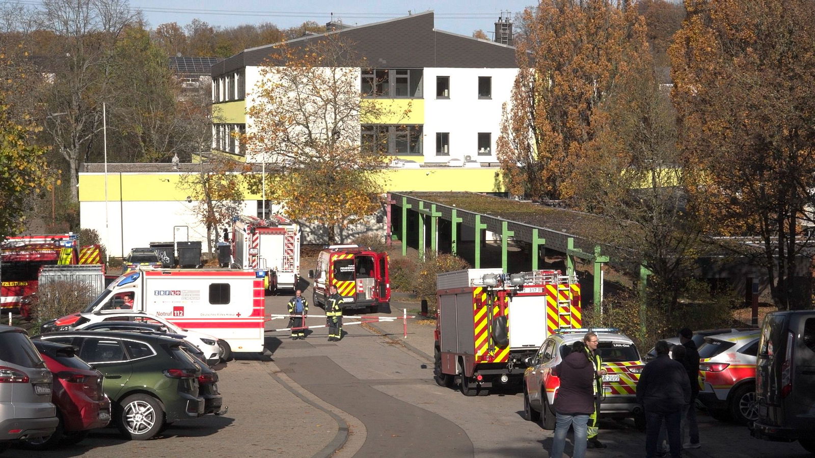 Feuerwehr und Krankenwagen stehen vor einer Schule, in der 32 Menschen mutmaßlich durch Reizgas verletzt wurden. Sie wurden von Einsatzkräften versorgt.