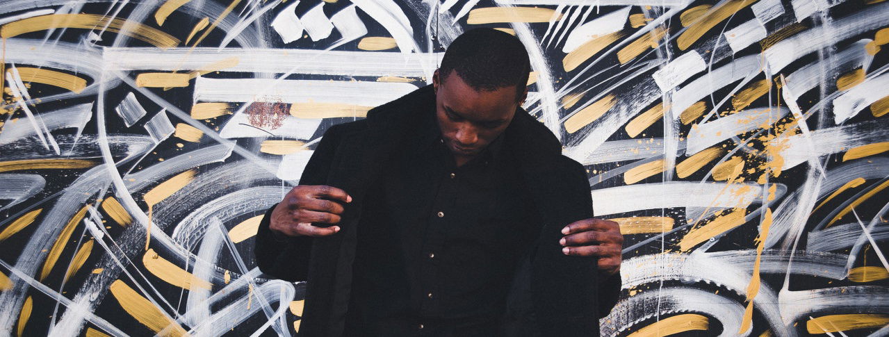 Mann schaut nach unten und richtet sich seine Jacke zurecht 