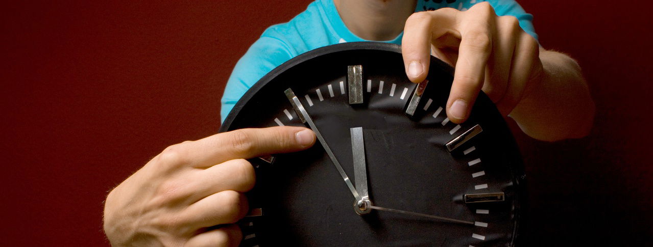 Mann zeigt mit Finger auf Uhrzeiger