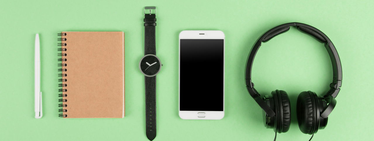 Grüner Hintergrund mit Notizbuch, Uhr, Handy und Kopfhörern