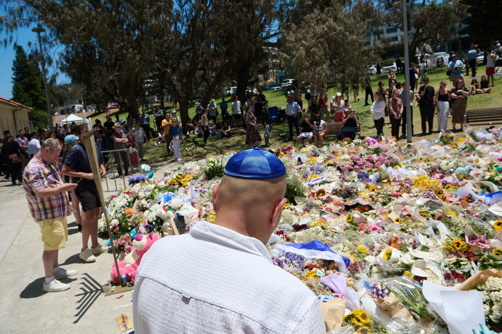 Menschen legen bei einer Gedenkfeier für die Opfer eines Terrorangriffs am Bondi Beach in Sydney Blumen nieder. (Foto aktuell)