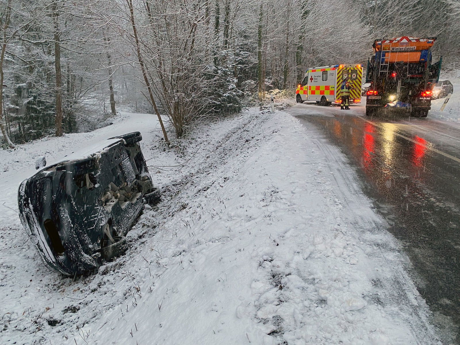 Streufahrzeuge streuen die Straße an der Unfallstelle. 