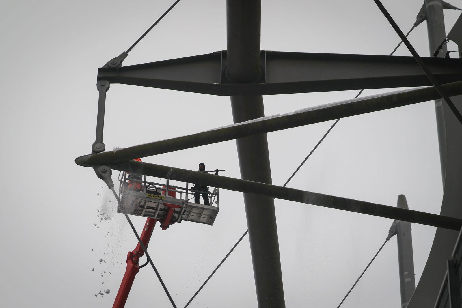 Arbeiter mit einem Hubsteiger entfernen Eis und Schnee von den Trägern des Stadiondachs in Hamburg.