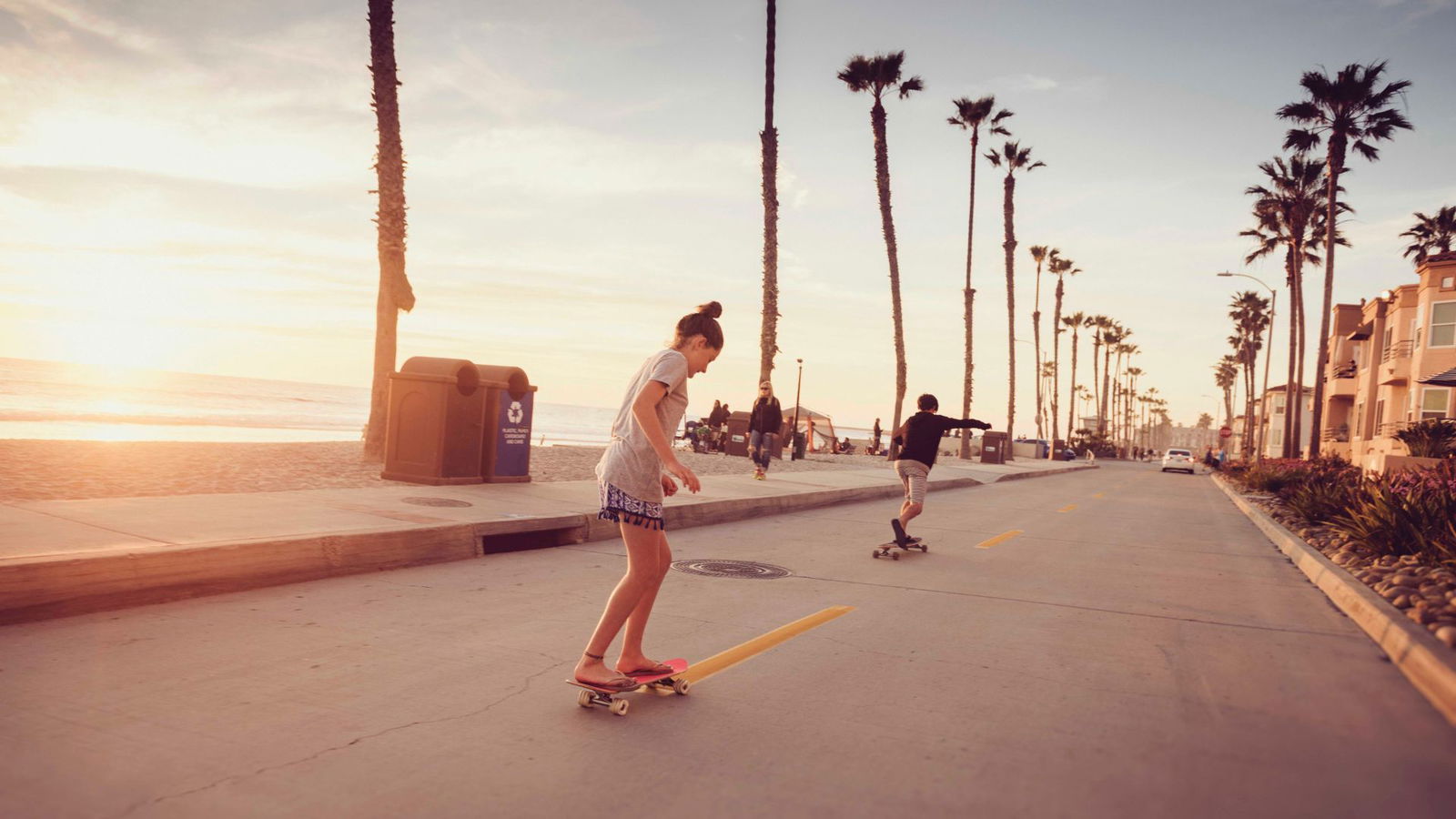 Mädchen fährt auf Skate Board in Los Angeles an Palmen vorbei