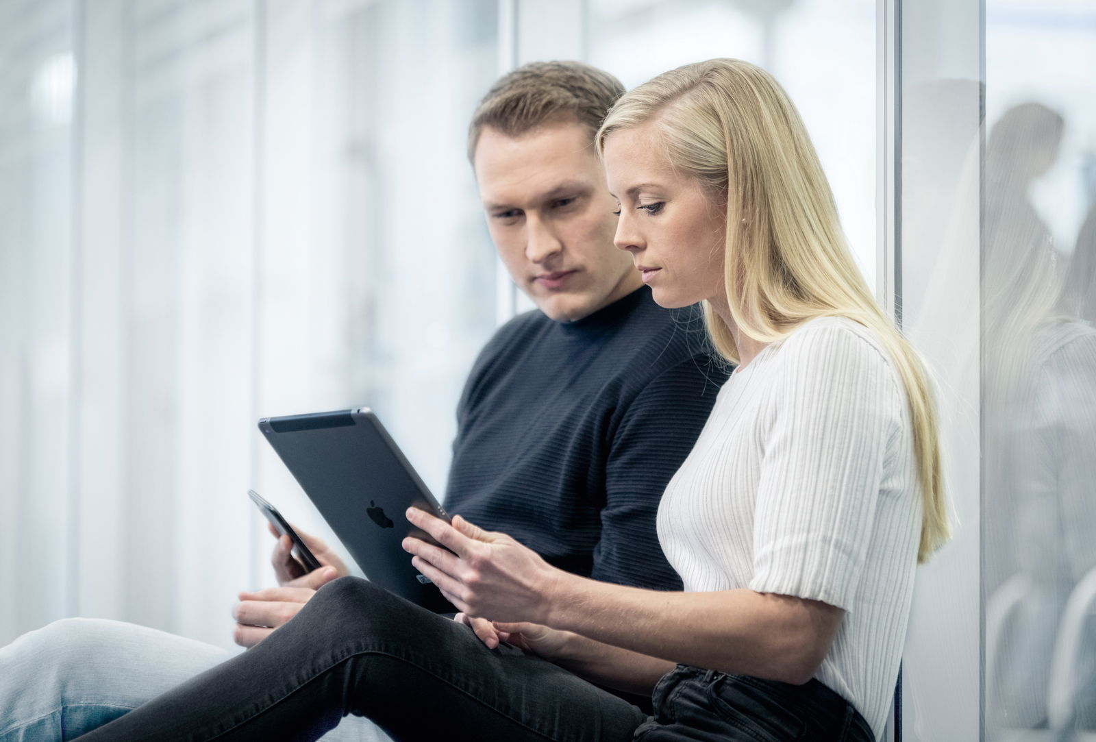 Festo_Lernzentrum_Mann und Frau sitzen auf dem Boden und schauen in ein Tablet