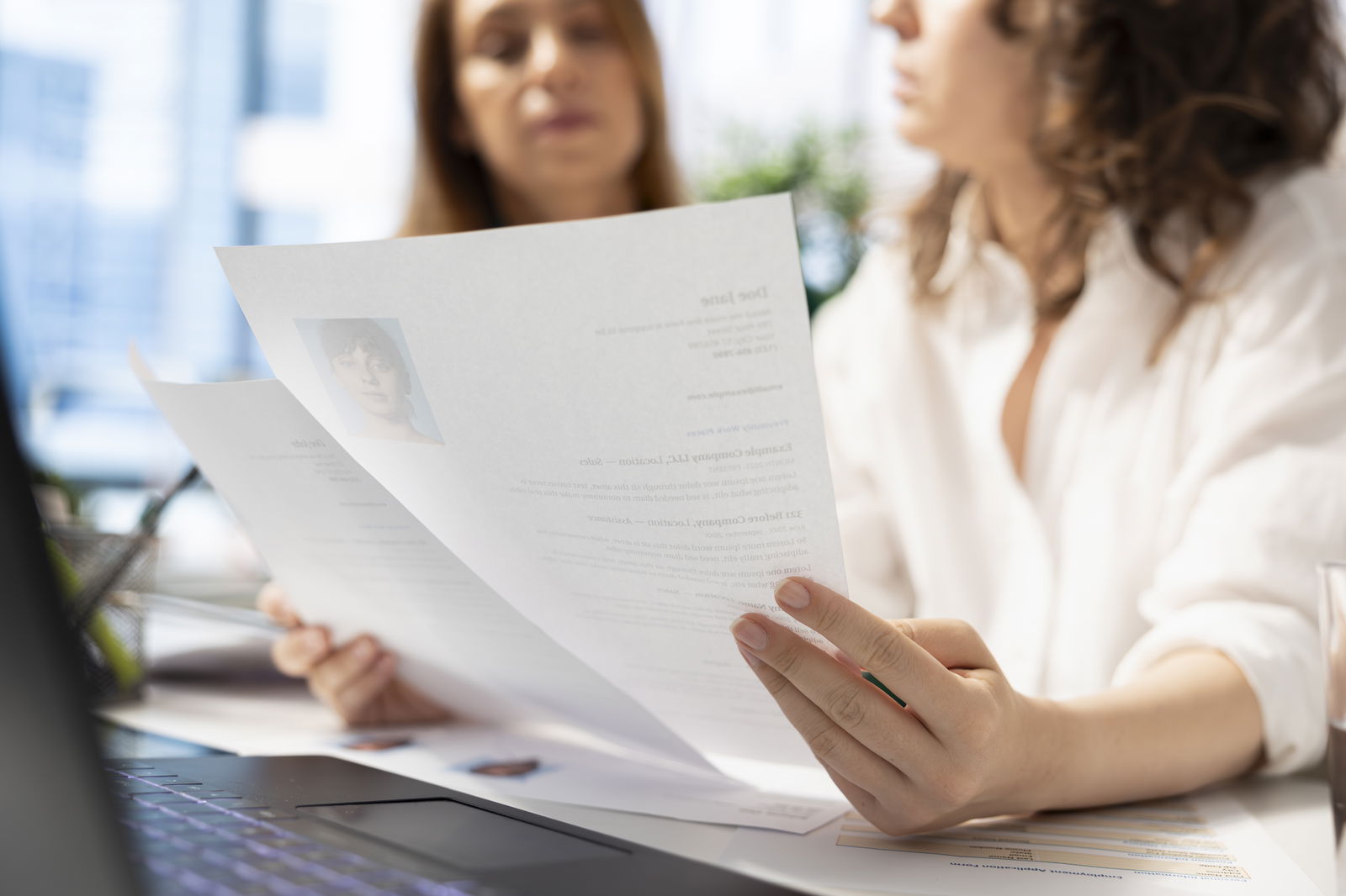 zwei Frauen schauen auf Bewerbungsunterlagen 
