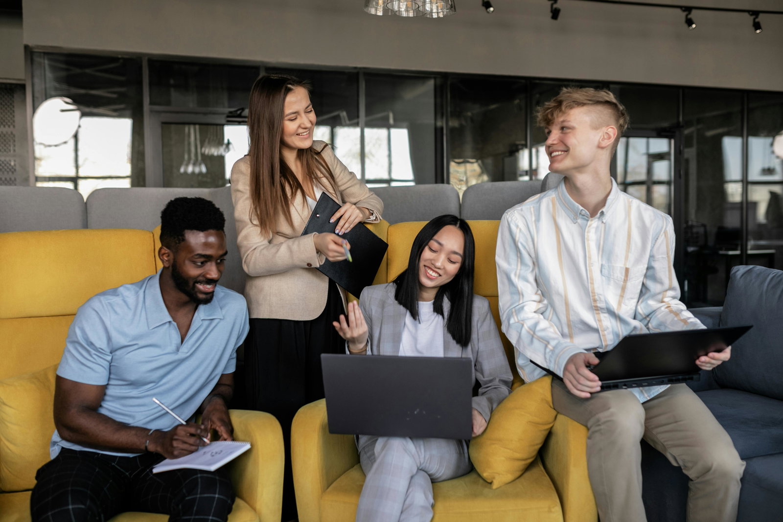Team sitzt au gelbem Sofa und schaut in einen Laptop