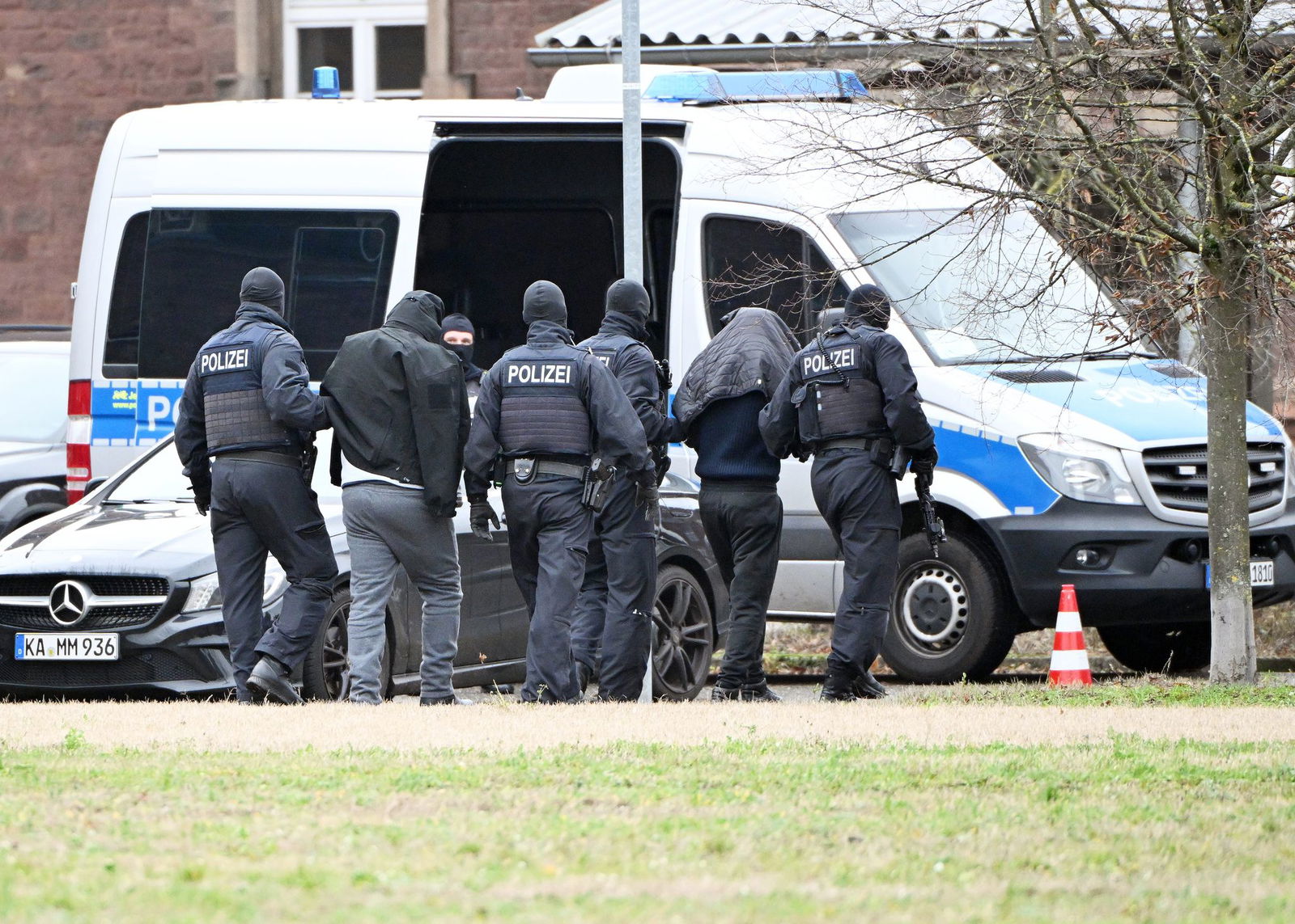 Zwei mutmaßliche Hamas-Mitglieder werden von Polizisten bei einem Hubschrauberlandeplatz von einem Hubschrauber zu einem Auto geführt. (Archivbild)