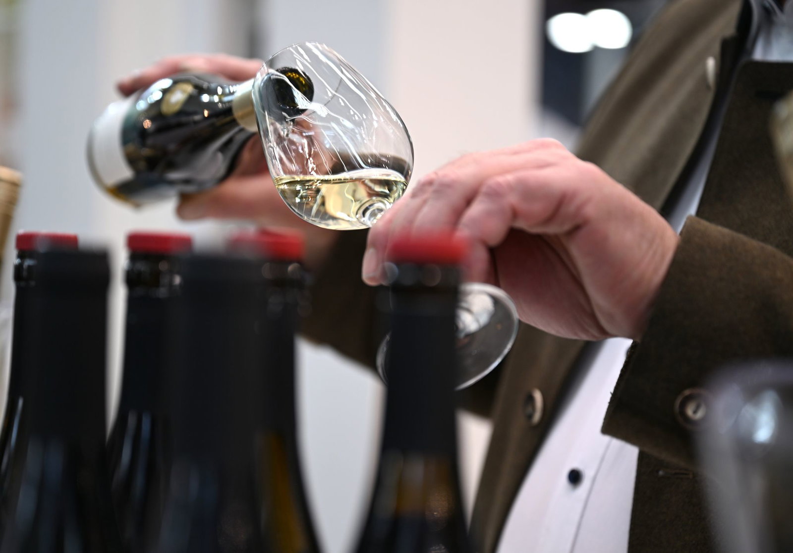 Ein Mitarbeiter des badischen Weinguts Bimmerle gießt am Prowein-Messe-Stand seiner Firma Riesling in ein Glas.