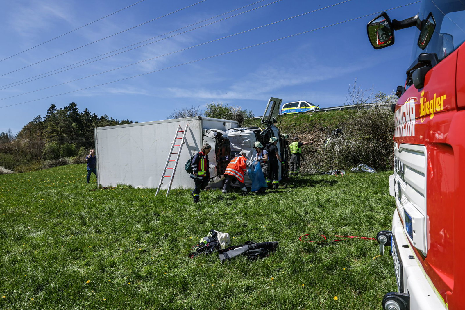 Der Lastwagen liegt umgekippt auf der Seite in einer Wiese.