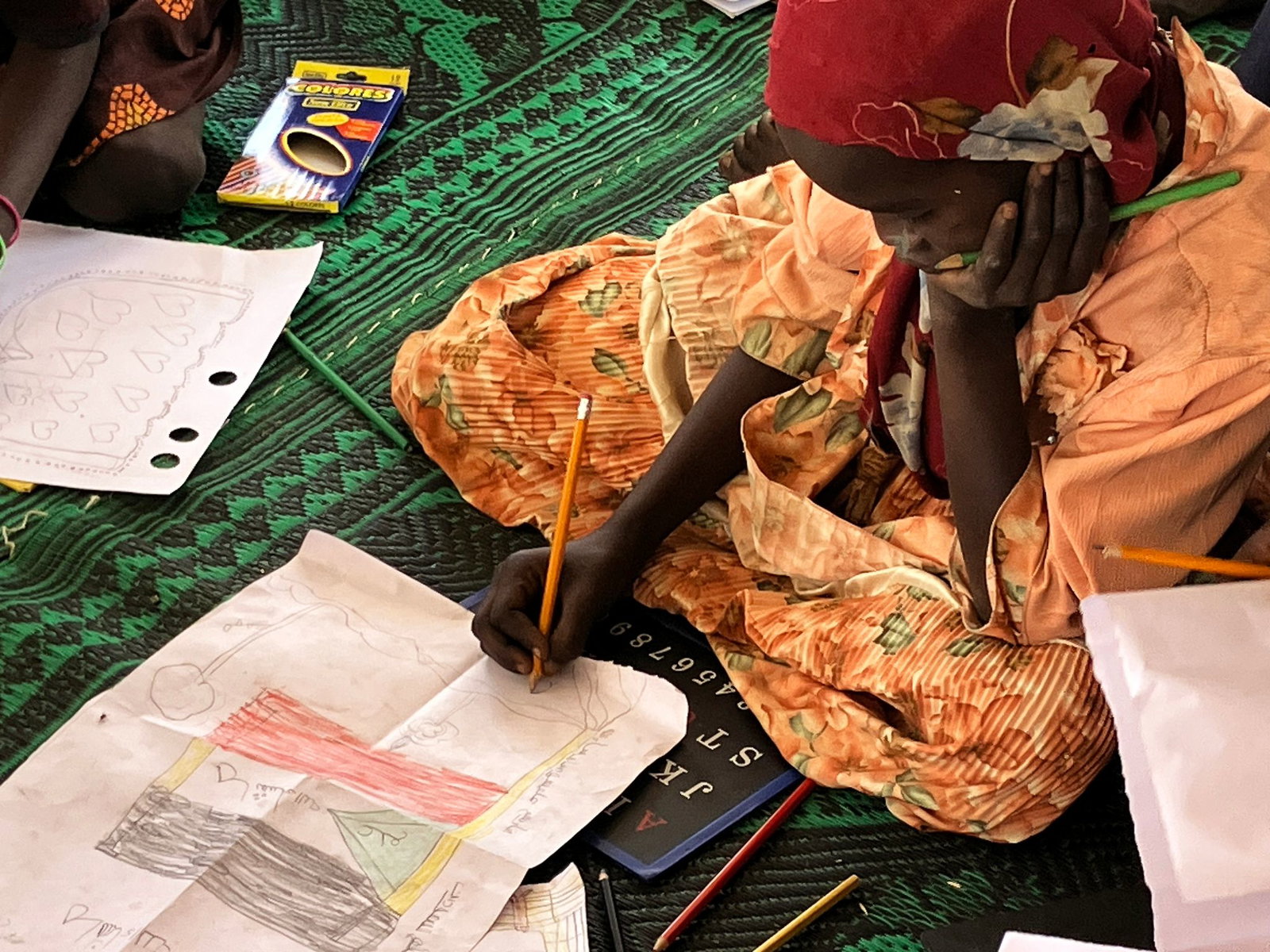 Ein kleines Mädchen malt die sudanesische Flagge.
