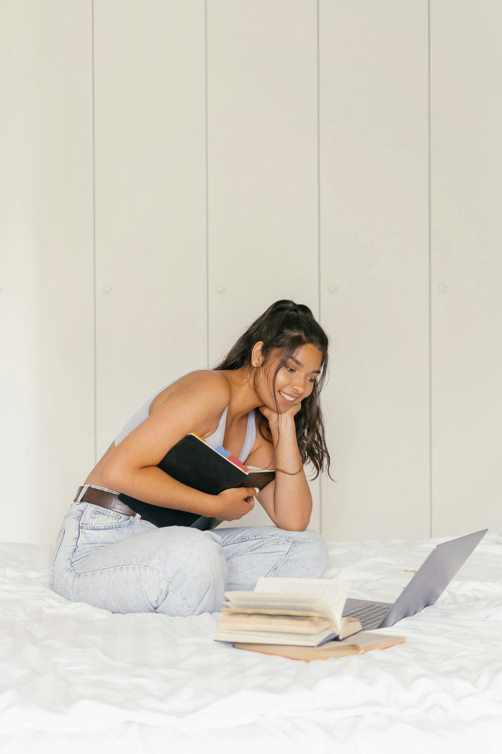Frau sitzt auch Bett mit Notizbuch und Laptop