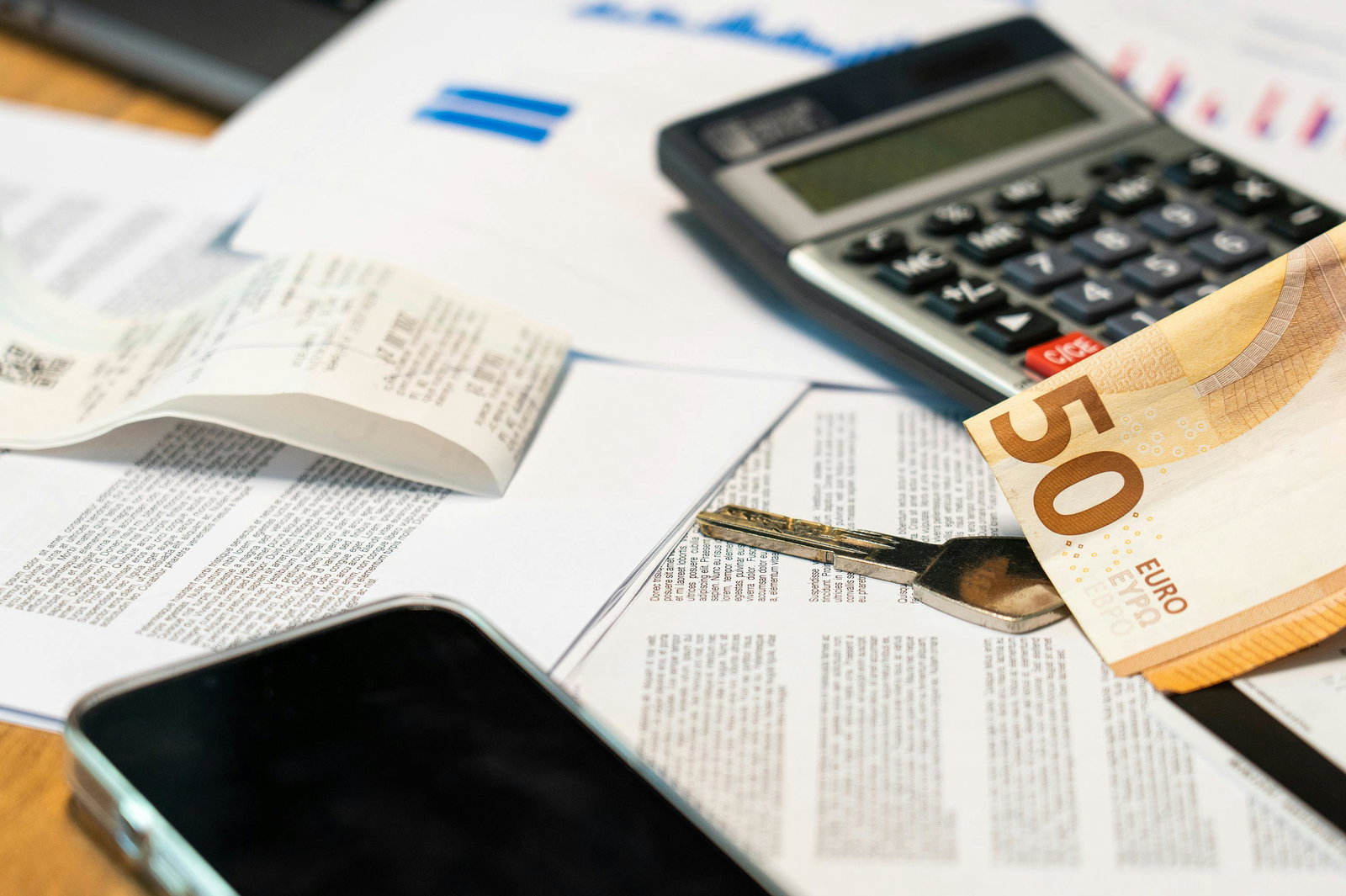 Taschenrechner liegt mit 50 Euro Schein auf Tisch mit Unterlagen