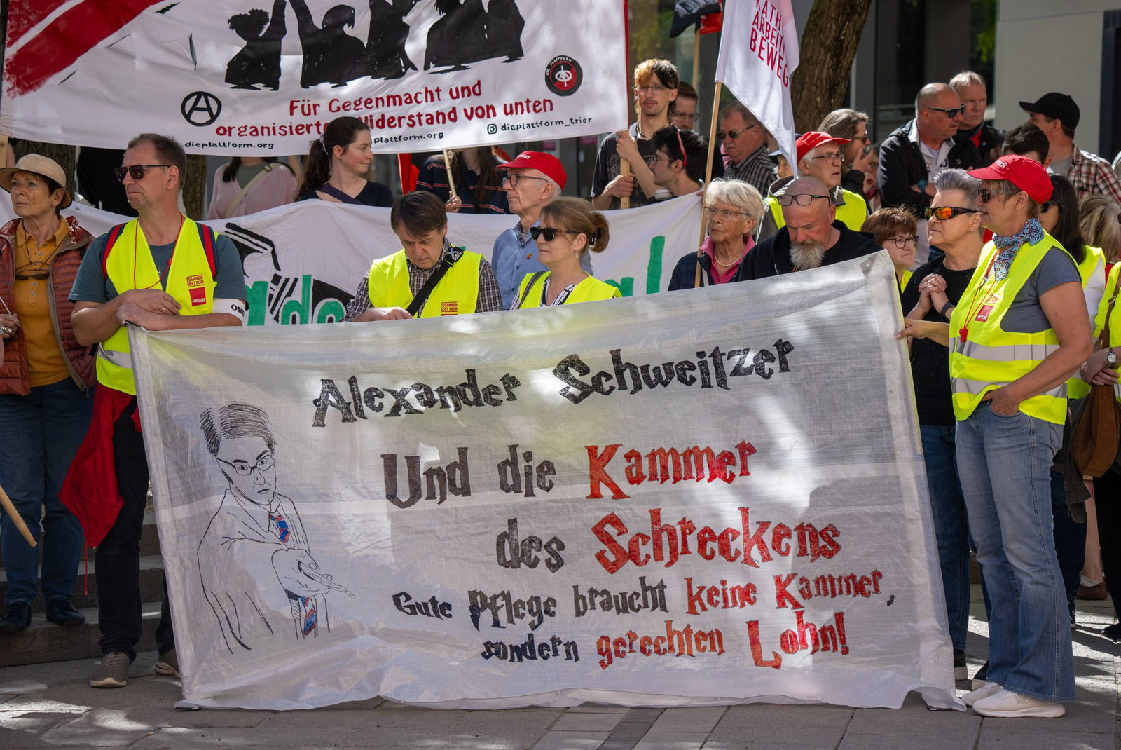 Gerechten Lohn in der Pflege fordern diese Demonstranten bei der zentralen DGB-Kundgebung in Trier und richten sich an den rheinland-pfälzischen Noch-Ministerpräsidenten Alexander Schweitzer (SPD).