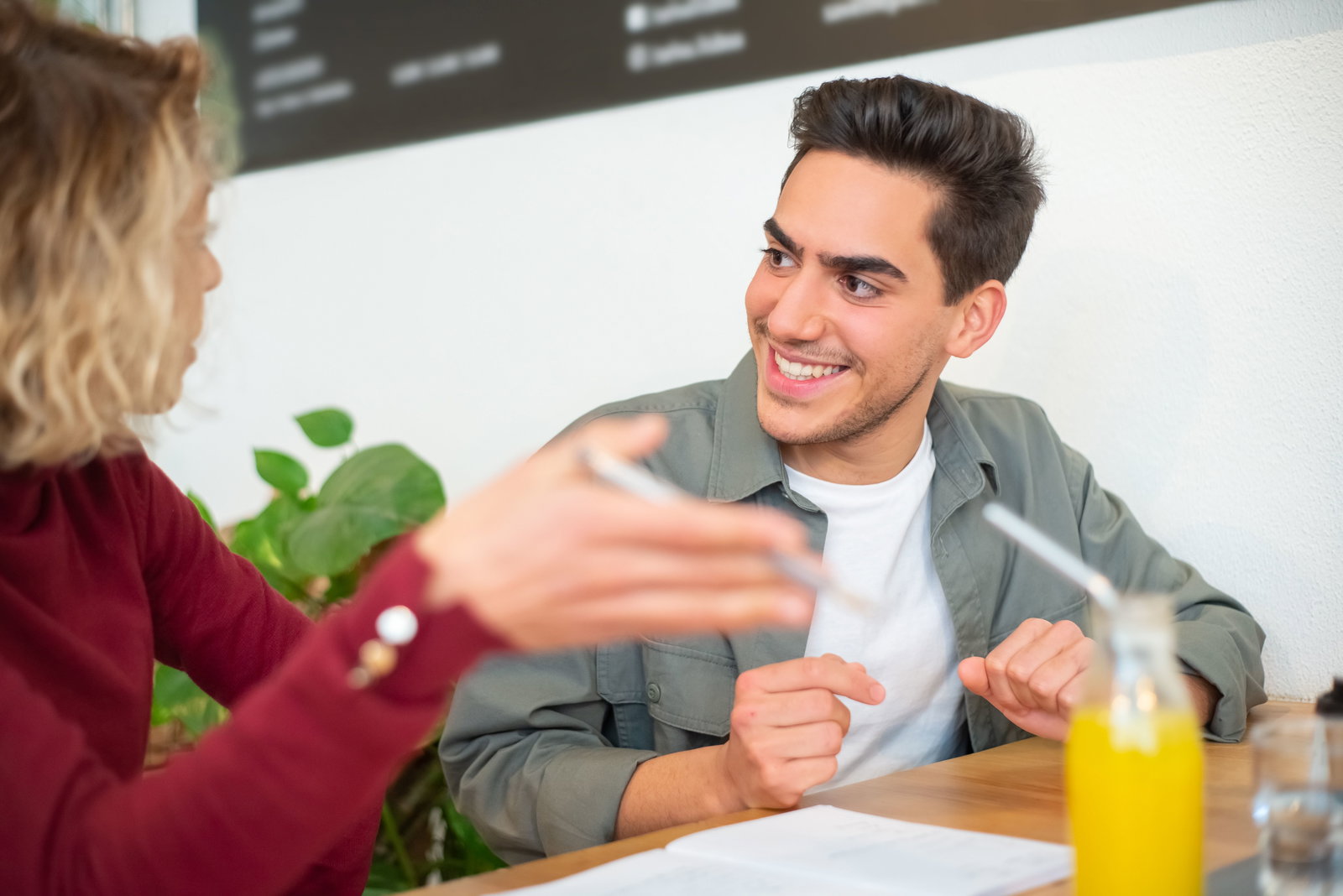 Mann schaut Frau an und lächelt während beide am Tisch sitzen