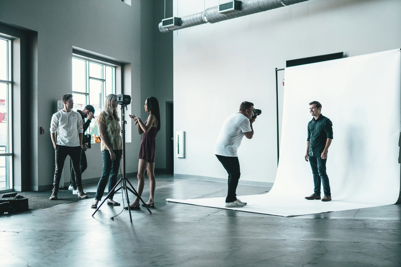 Fotograf macht Bilder vor einer Weißen Wand von mehreren Models