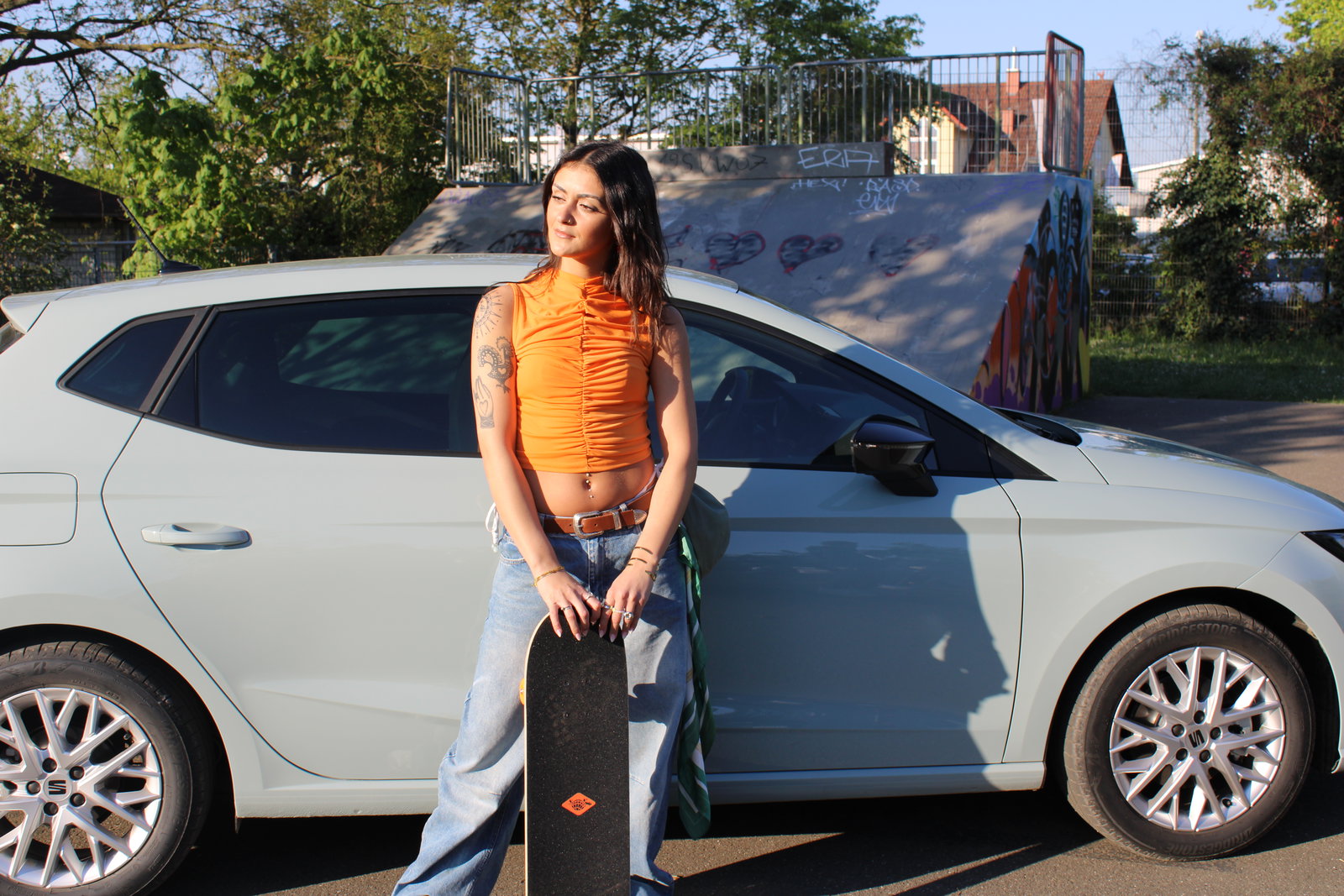Filiz steht vor dem SEAT Ibiza auf einem Skatepark
