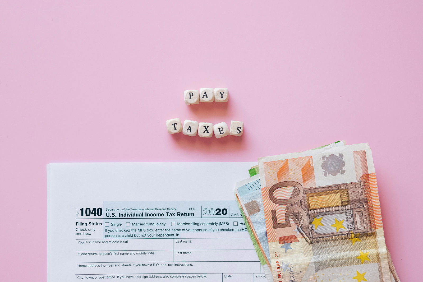 Steuererklärung liegt mit 50 Euroschein auf Pinkem Hintergrund mit Überschrift "Pax Taxes"