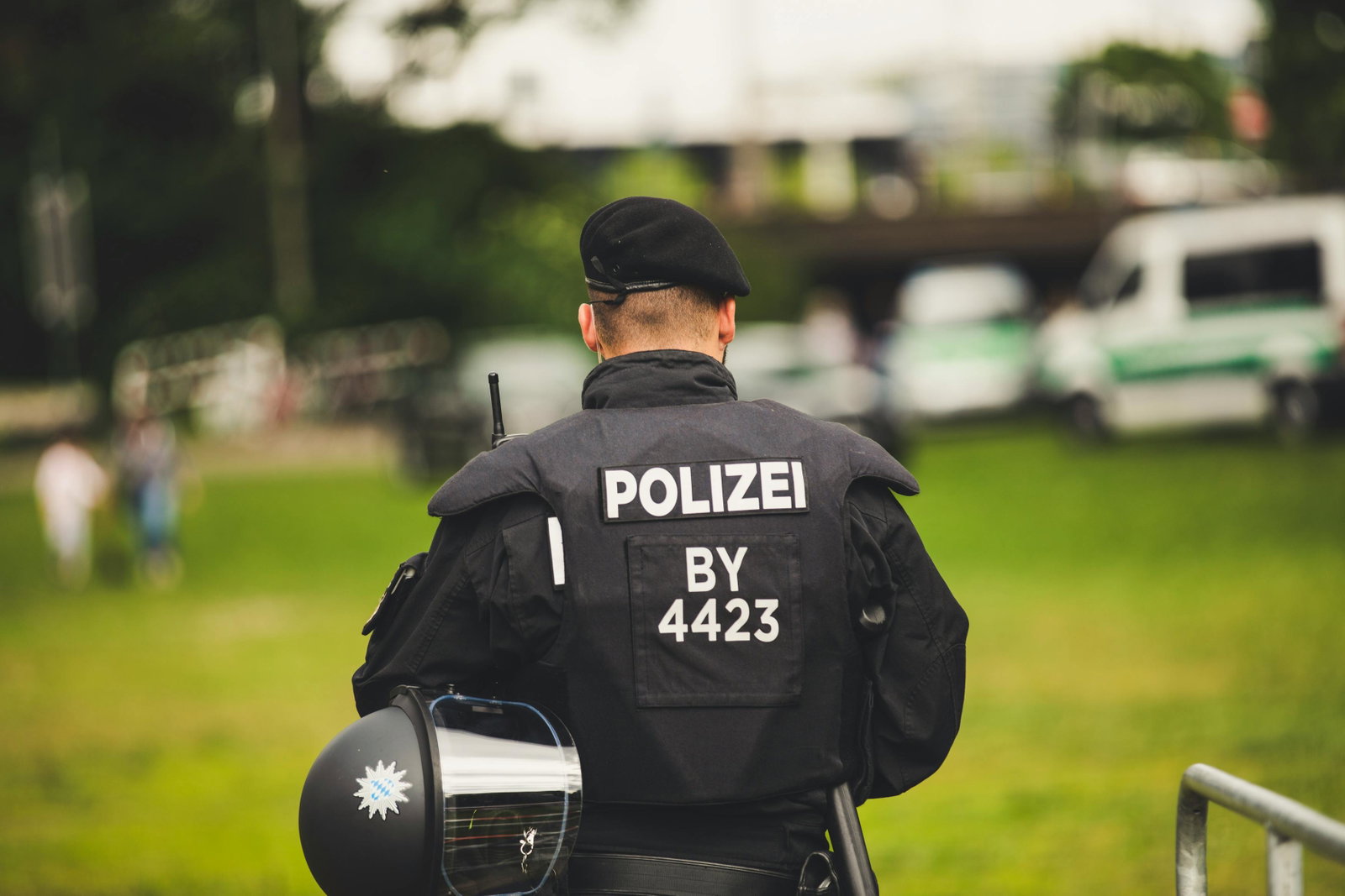 Polizist in Uniform mit Schutzweste steht mit dem Rücken zur Kamera und trägt Mütze