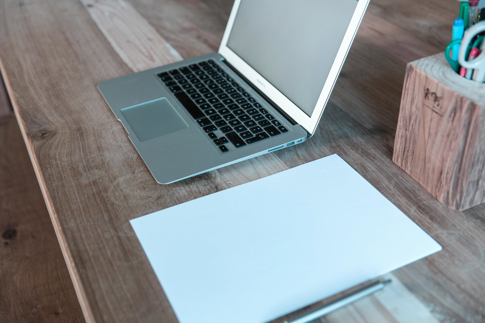 Laptop liegt neben Papier auf einem Schreibtisch  