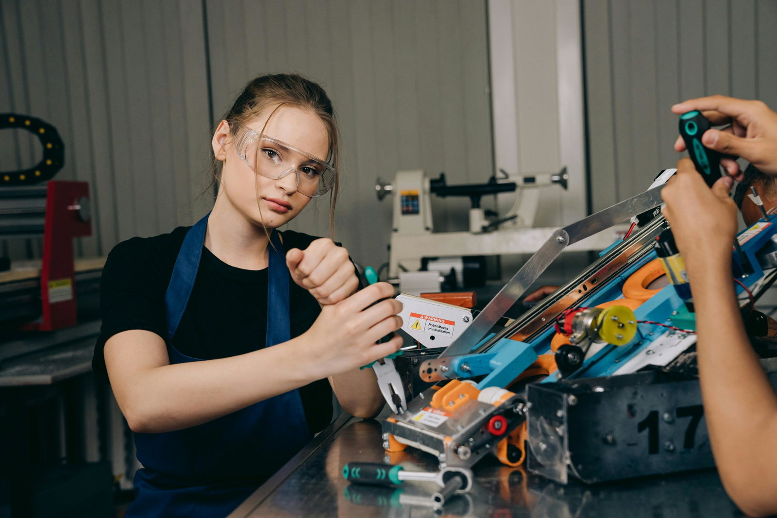 Anlagenmechanikerin arbeitet und trägt Schutzbrille und schaut dabei in die Kamera