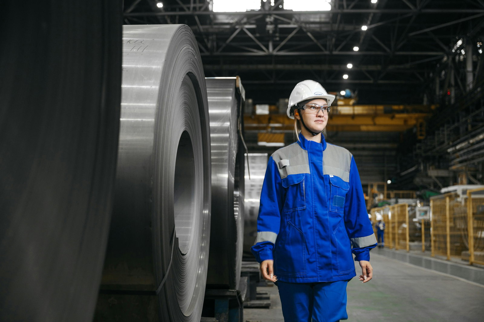 Werkzeugmechanikerin in Blaumann läuft durch Werkzeugraum