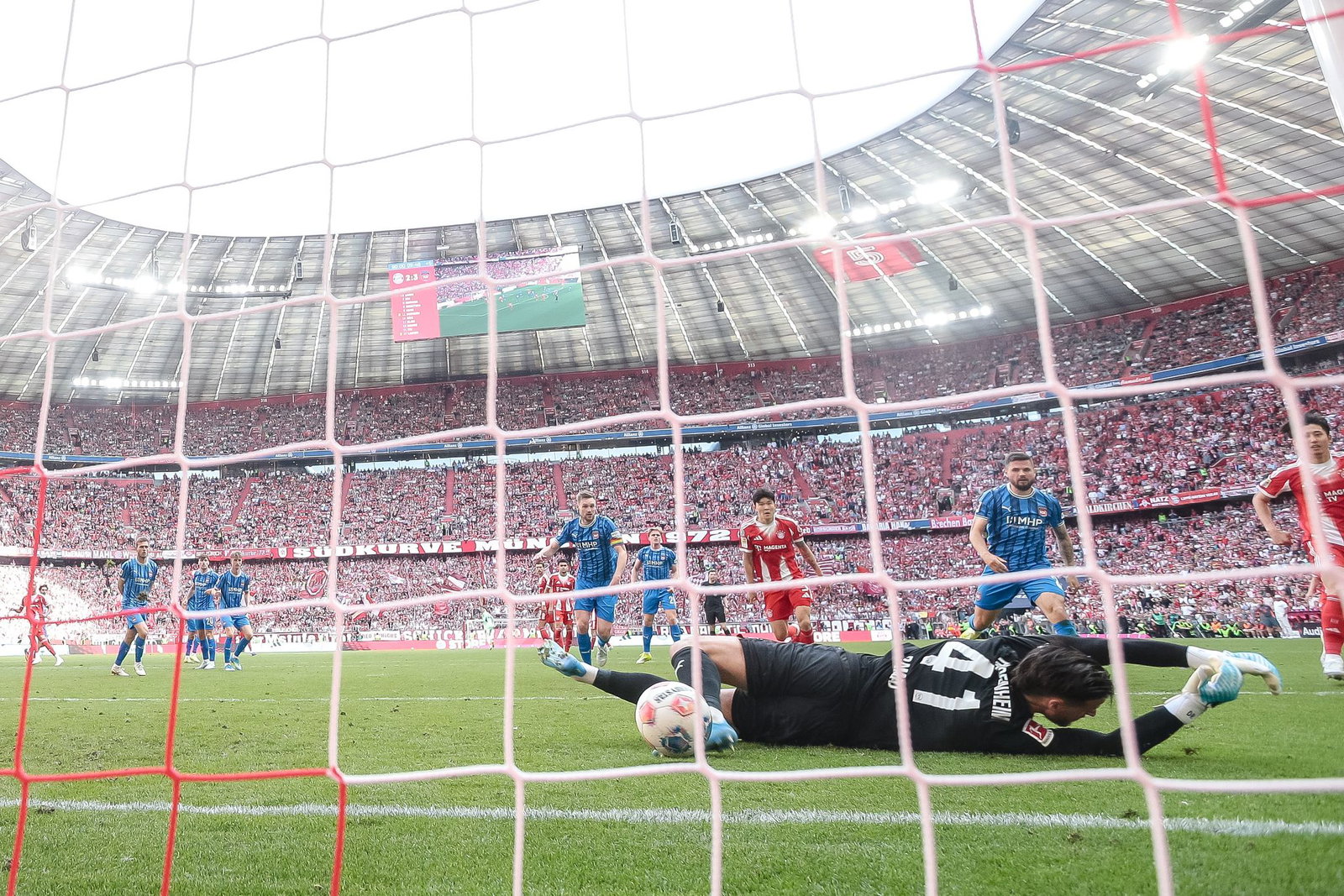 Nach dem Schuss von Michael Olise prallt der Ball vom Pfosten an den Fuß von Heidenheims Torwart Diant Ramaj und von dort zum 3:3 ins Tor. 
