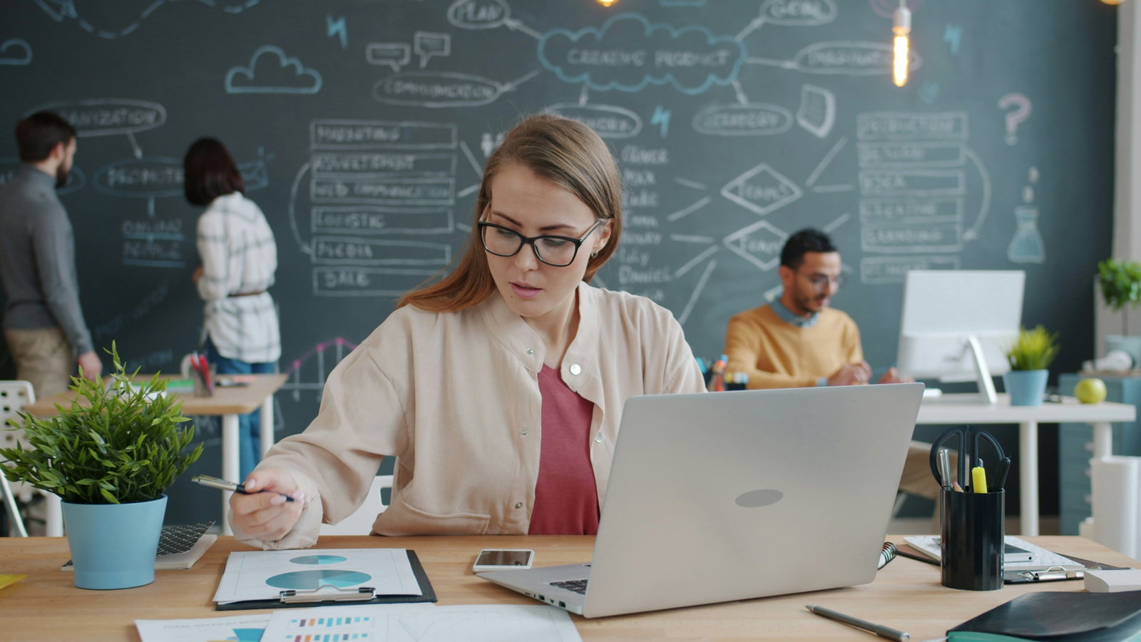 Frau am arbeiten am Computer und schreiben mit Stift in der Hand