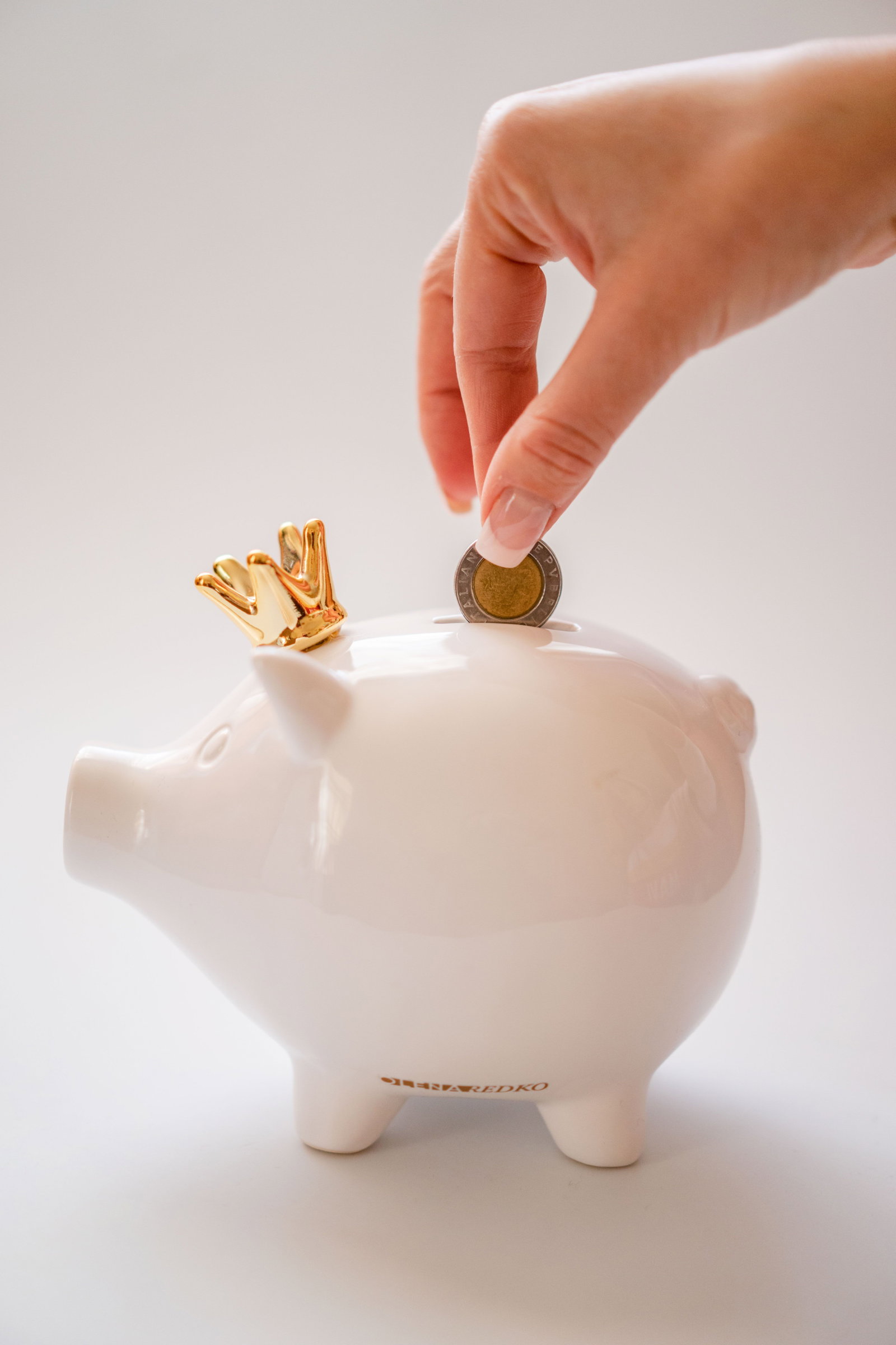 Sparschwein und Finger die 2 Euro in dieses geben