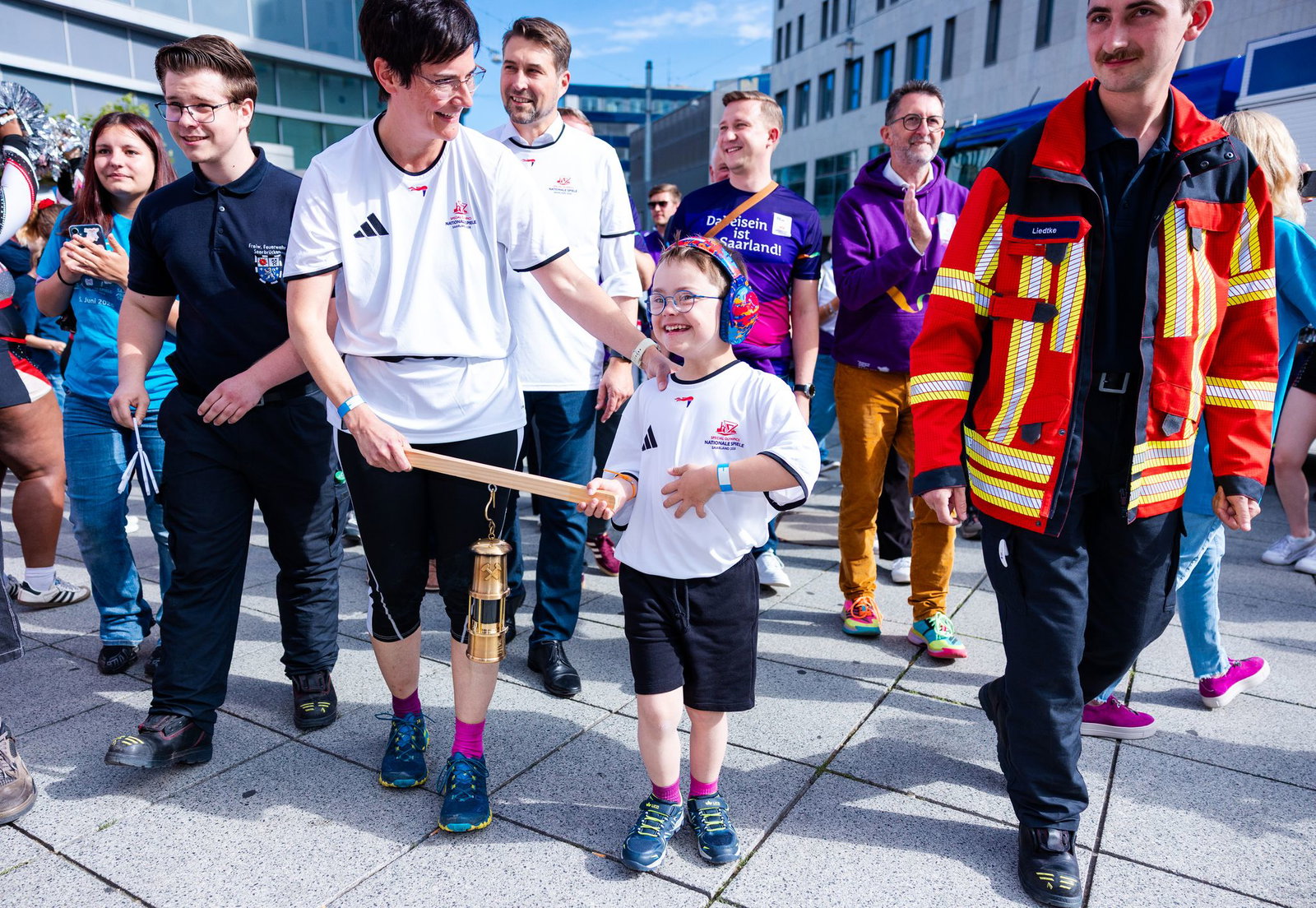 Elias (8) trägt gemeinsam mit seiner Mutter Stephanie Lade die Grubenlampe, das Symbol des Fackellaufs der Special Olympics, auf einem Holzträger durch die Saarbrücker Innenstadt.
