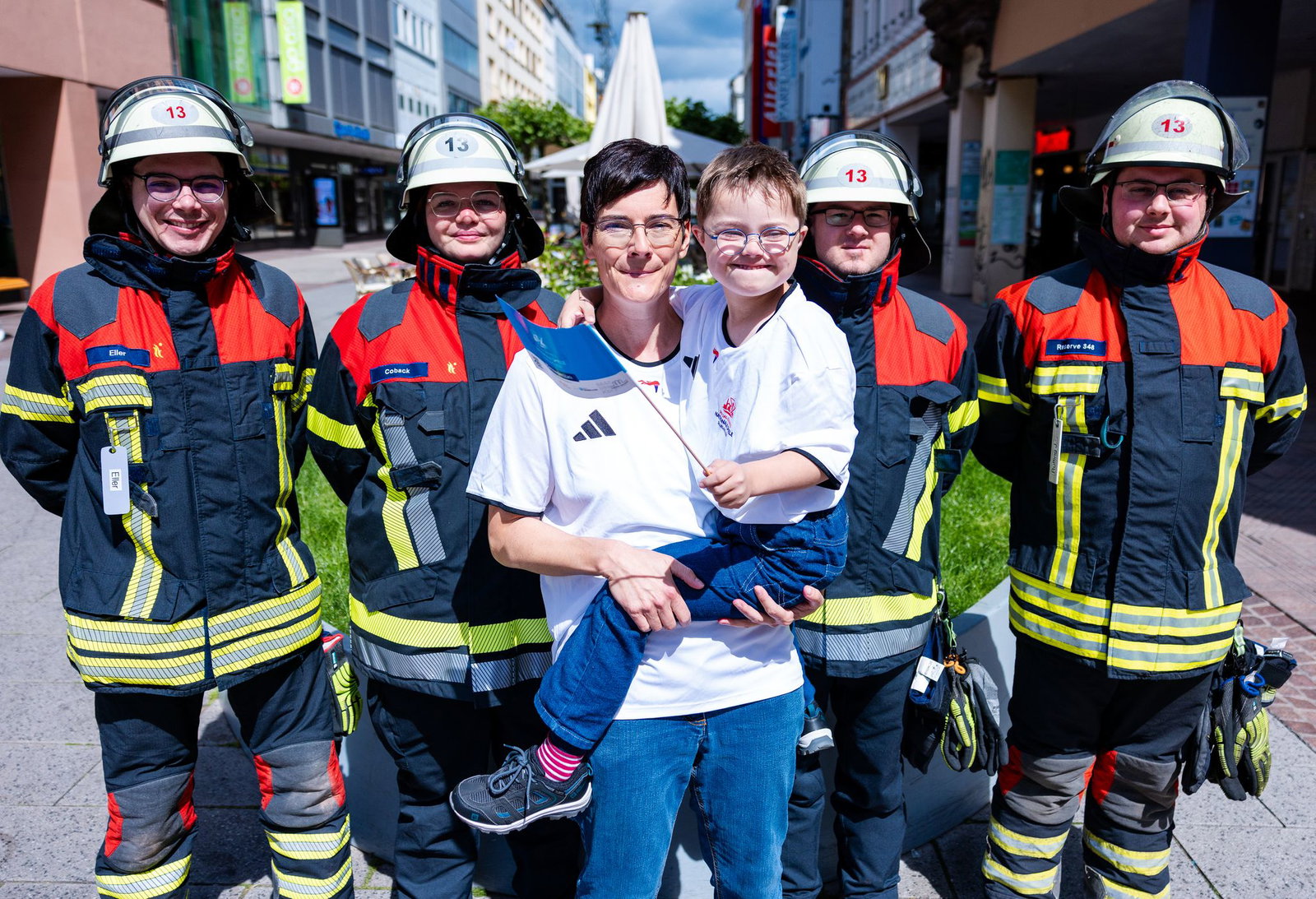Einsatzkräfte der Freiwilligen Feuerwehr Saarbrücken-St. Johann (LB 13) wünschen dem achtjährigen Elias und seiner Mutter Stephanie Lade vor dem Fackellauf der Special Olympics viel Erfolg.