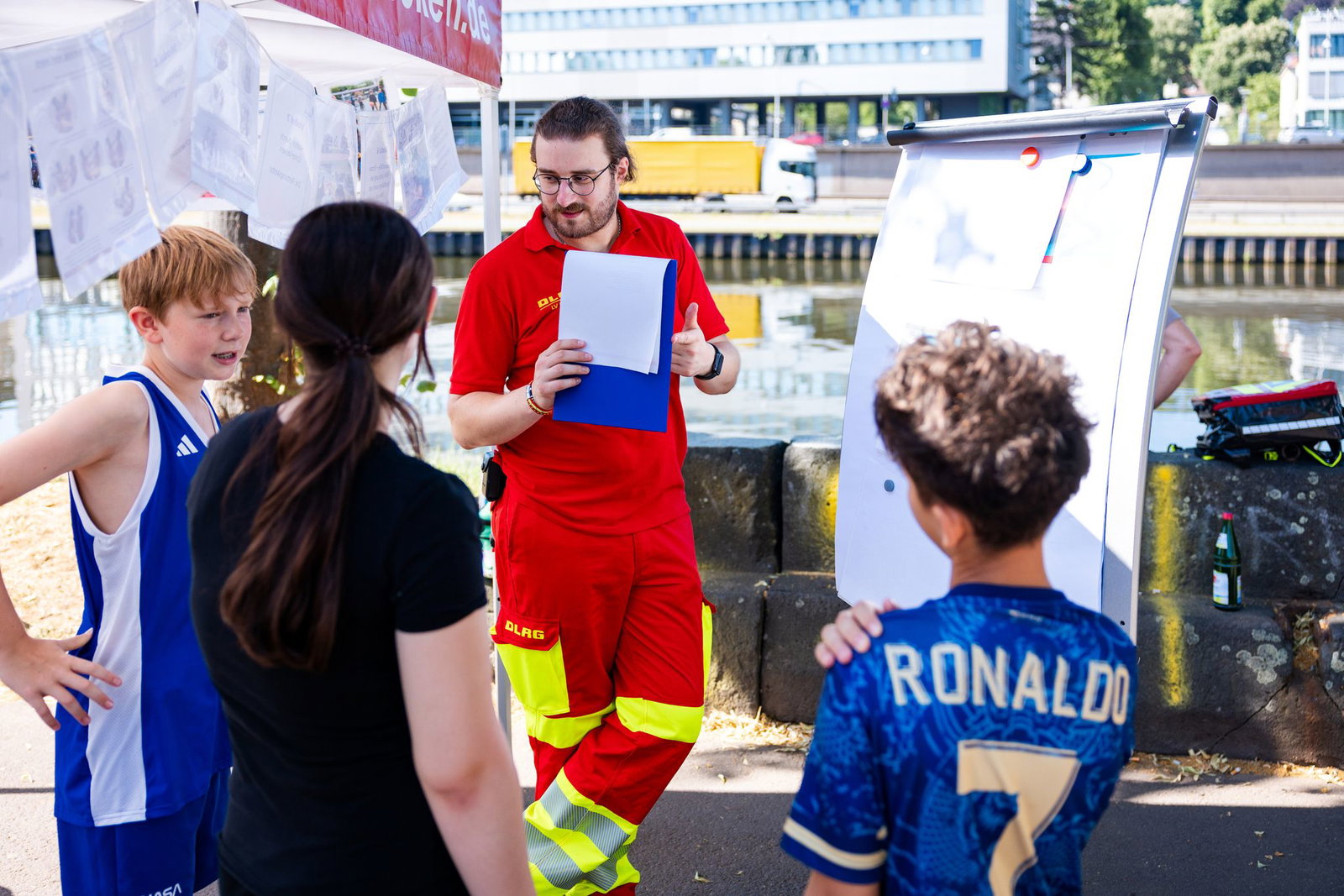 Ein DLRG-Ausbilder erklärt Schülerinnen und Schüler aus Saarbrücken Gefahren am Wasser und die richtigen Verhaltensweisen im Notfall.