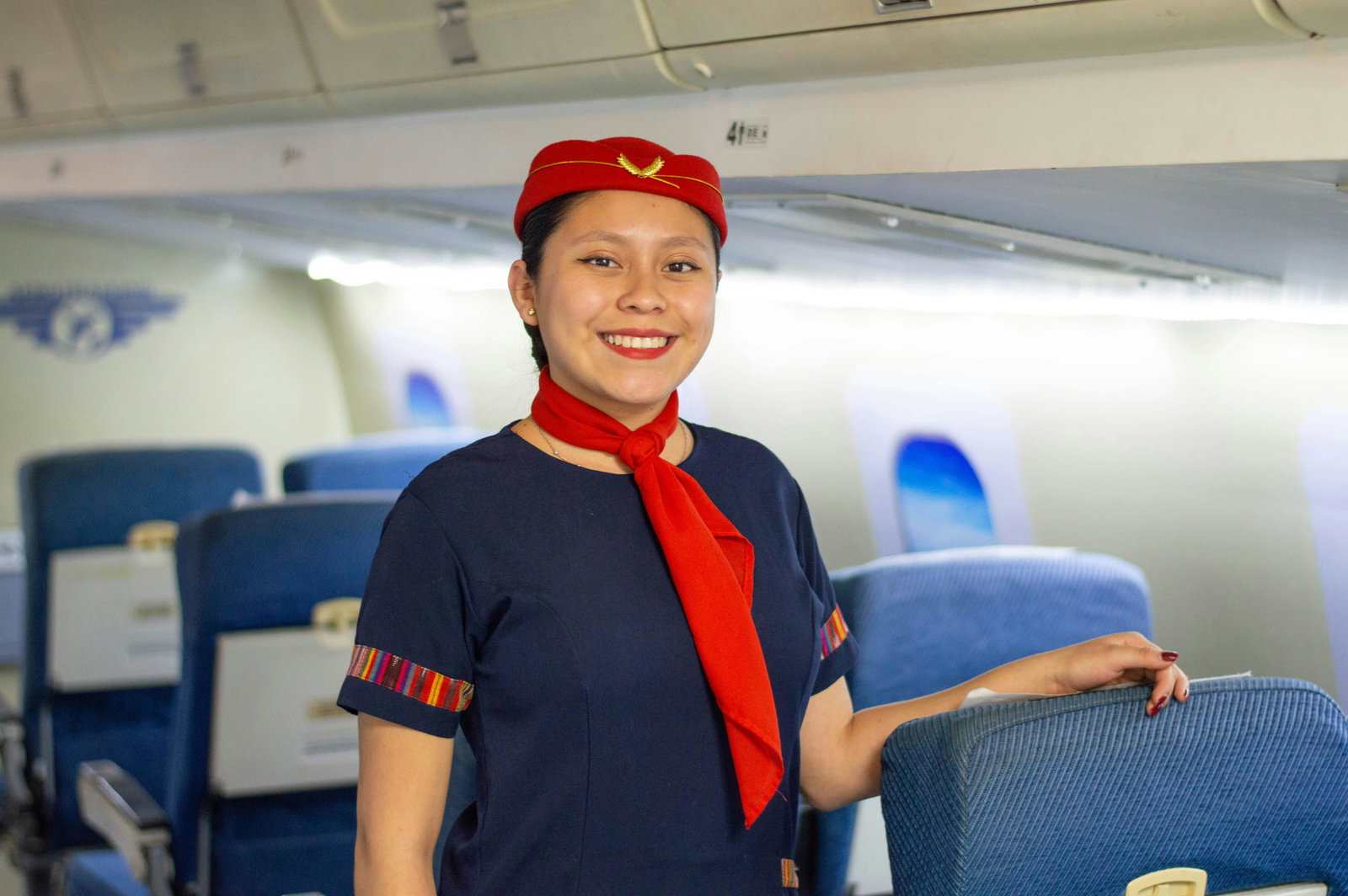 Flugbegleiterin in Uniform steht im Flugzeug und schaut in die Kamera
