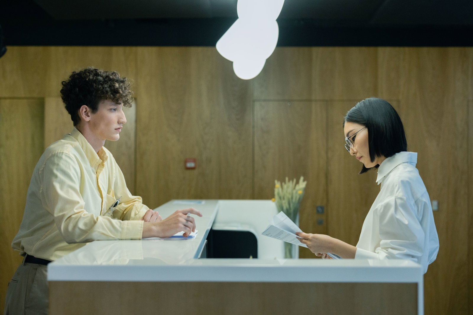 Hotelmanager steht am check In und schaut auf Unterlagen von Kunden